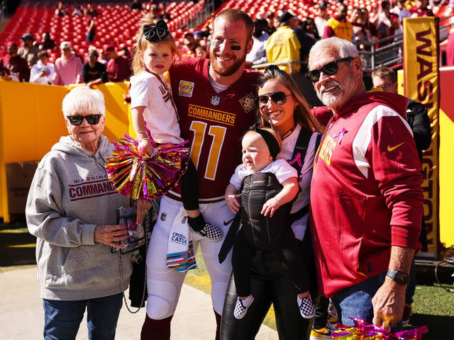 <p>Scott Taetsch/Getty</p> Carson Wentz with his wife, Madison, and his parents before the game against the Tennessee Titans in 2022