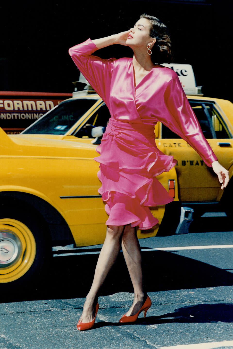 <p>A model wears a fuchsia dress and jeweled earrings out on the street. </p>