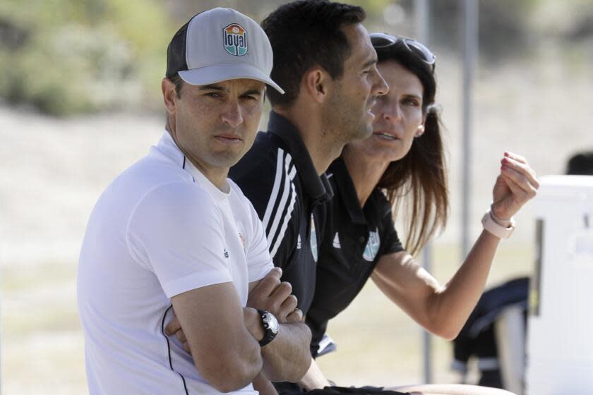 Landon Donovan, left, wears a baseball cap with his arms folded while sitting next to his San Diego Loyal assistant coaches