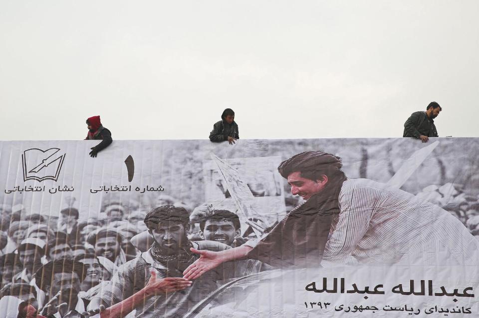 FILE - In this file photo taken on Sunday, Feb. 2, 2014, Afghans erect an election poster of presidential election candidate, Abdullah Abdullah in Kabul, Afghanistan. (AP Photo/Massoud Hossaini, File)