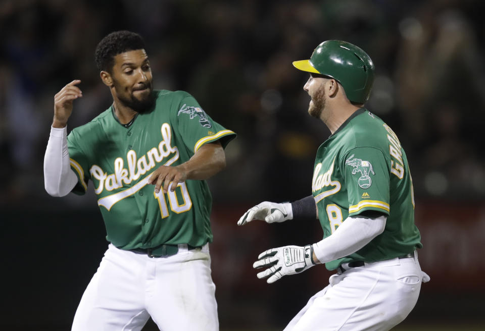 Oakland Athletics' Robbie Grossman, right, celebrates with Marcus Semien after making the game-winning hit in the 13th inning of a baseball game against the Houston Astros Friday, Aug. 16, 2019, in Oakland, Calif. (AP Photo/Ben Margot)