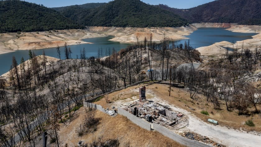 FILE - In this May 23, 2021, file photo, a home destroyed in the 2020 North Complex Fire sits above Lake Oroville, in Oroville, Calif. California officials say the drought gripping the U.S. West is so severe it could cause one of the state's most important reservoirs to reach historic lows by late August, closing most boat ramps and shutting down a hydroelectric power plant during the peak demand of the hottest part of the summer. (AP Photo/Noah Berger, File)