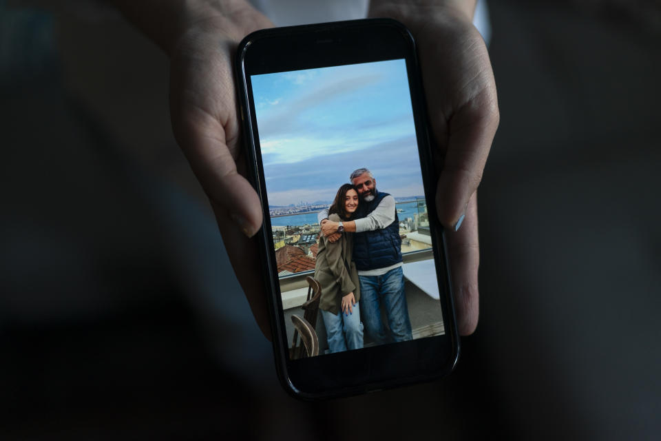 Leili Ghazi, a 22-year-old immigrant from Iran, poses with a photo taken with her father, Mehrdad, in Pasadena, Calif., Tuesday, June 21, 2022. Two years ago, Leili Ghazi quit studying biomedical engineering in Iran and seized the chance to travel to the United States to build a new life for herself and her parents. Now, the 22-year-old is separated indefinitely from her family because her father performed military service more than two decades ago for a branch of the Iranian armed forces that the U.S. government has declared a foreign terrorist organization. (AP Photo/Jae C. Hong)