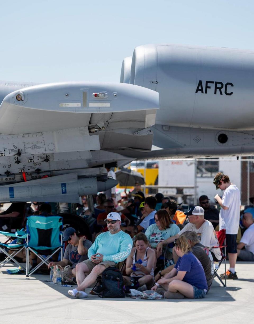 Dozens of people find relief from the sun in the shadow of an A-10 Thunderbolt during the Garmin KC Air Show on Saturday, Aug. 19, 2023, in New Century.