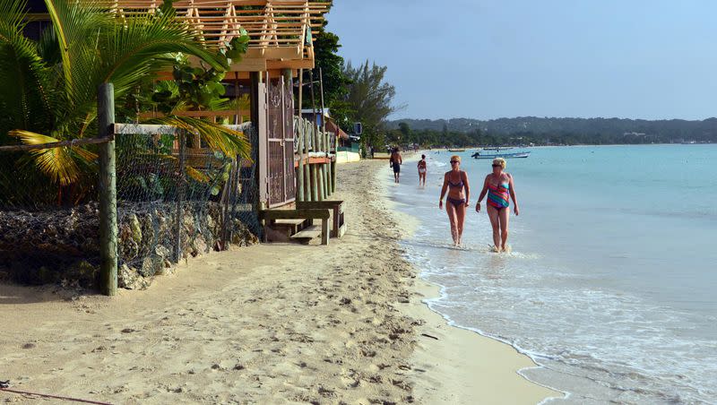 Sunbathers walk along a badly eroding patch of resort-lined crescent beach in Negril in western Jamaica in this 2014 file photo.