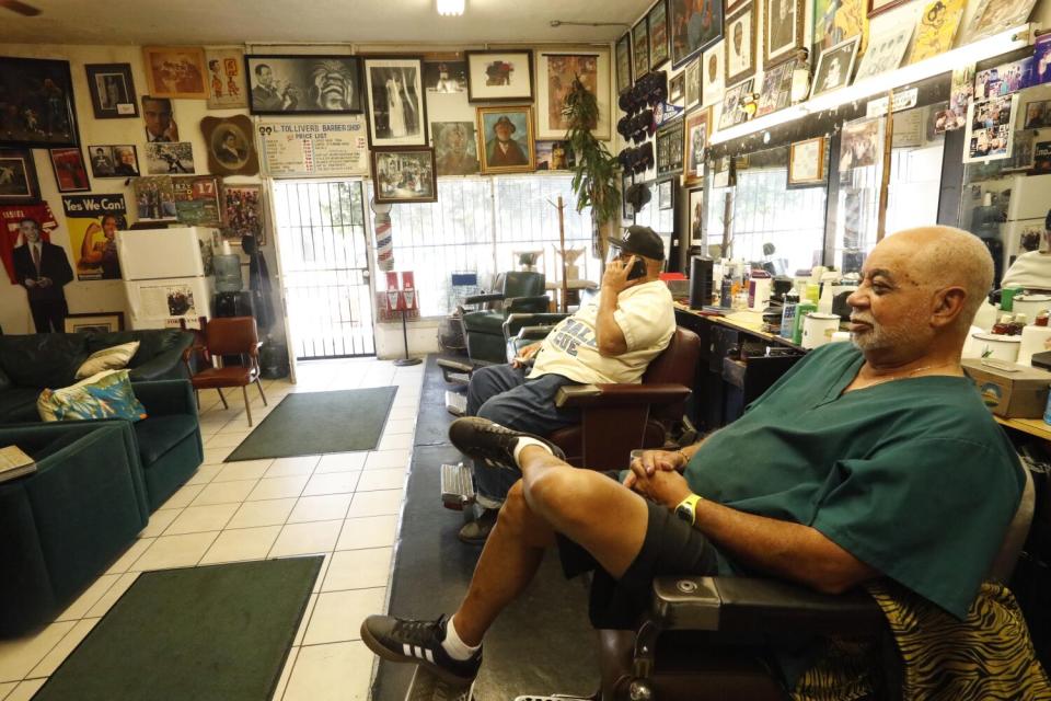 Лоуренс Толливер (справа) ждет клиентов в своей знаменитой парикмахерской Tolliver's в Южном Лос-Анджелесе, 2019 год.