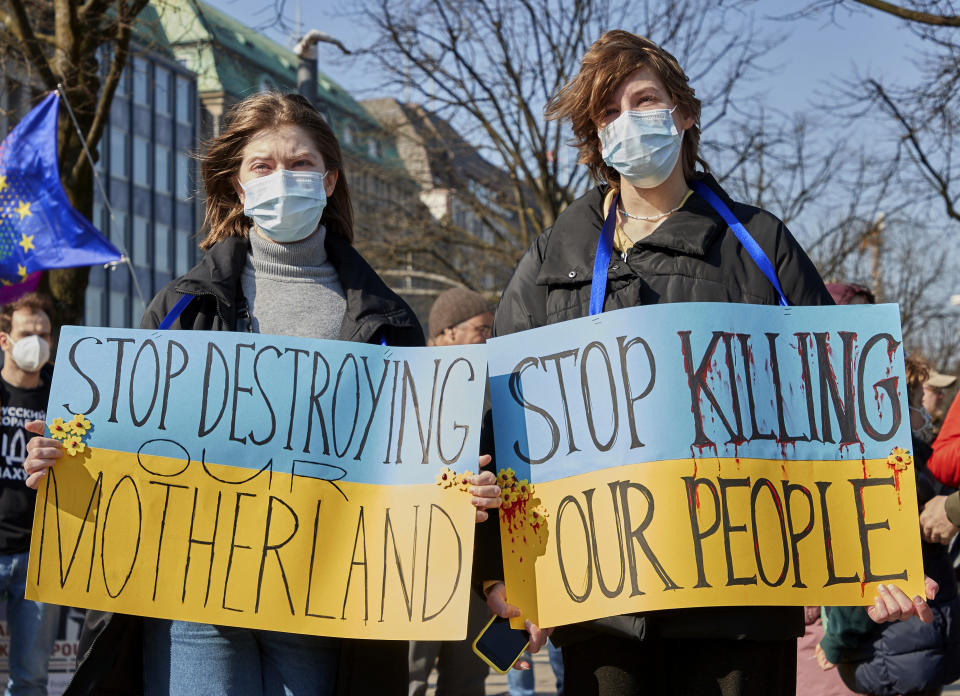 The Ukrainian refugees Olia, and Solomiia from Rivne in western Ukraine take part in the demonstration "Peace in Ukraine - Security in Europe" holding banners reading "Stop destroying our motherland" and "Stop killing our people" in Hamburg, Germany, Sunday, March 22, 2022. (Georg Wendt/dpa via AP)