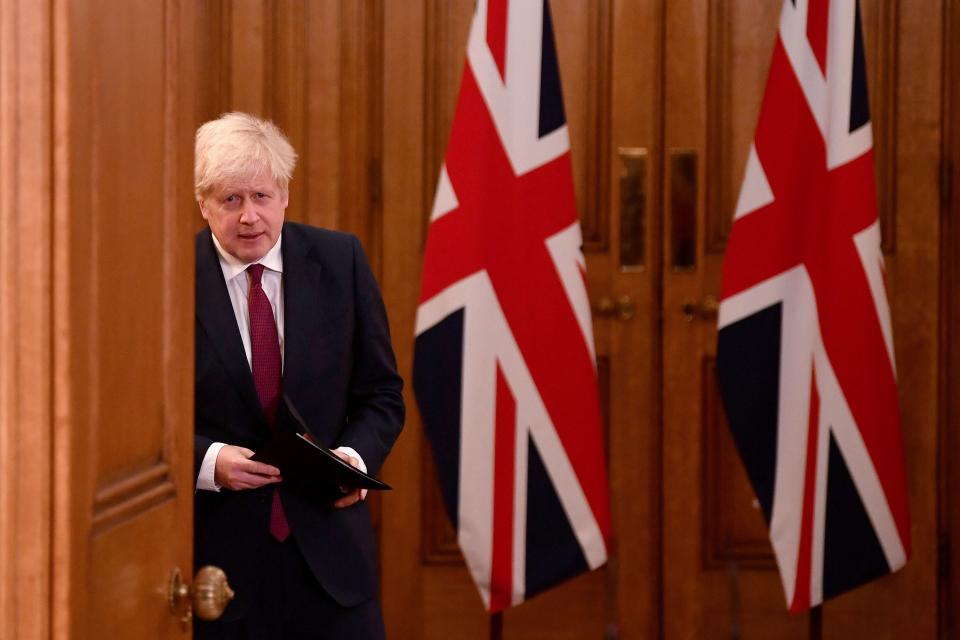 Britain's Prime Minister Boris Johnson walks past union flags as he arrives to attend a virtual press conference inside 10 Downing Street in central London on December 19, 2020. - British Prime Minister Boris Johnson on Saturday announced a "stay at home" order for London and southeast England to slow a new coronavirus strain that is significantly more infectious. The new strain of the virus "does appear to be passed on significantly more easily," Johnson said at a televised briefing. He ordered new restrictions for London and south-eastern England from Sunday, saying that under the new "tier four" rules, "residents in those areas must stay at home" at least until December 30. (Photo by TOBY MELVILLE / POOL / AFP) (Photo by TOBY MELVILLE/POOL/AFP via Getty Images)