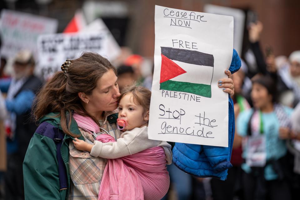 A woman kisses her 2-year-old daugher as she holds up a sign urging "Free Palestine" and "Stop the Genocide" while participating in the "All Out for Gaza" rally and march at the Ohio Statehouse Saturday.