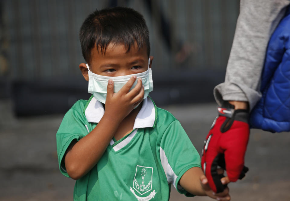 In this Wednesday, Jan. 30, 2019, file photo, a young boy wears a protective mask for the high levels of air pollution as he's picked up from school in Bangkok, Thailand. Over 400 schools in Bangkok have been ordered shut Wednesday as the Thai capital sees continuously high levels of air pollution and dust particles. (AP Photo/Sakchai Lalit, File)