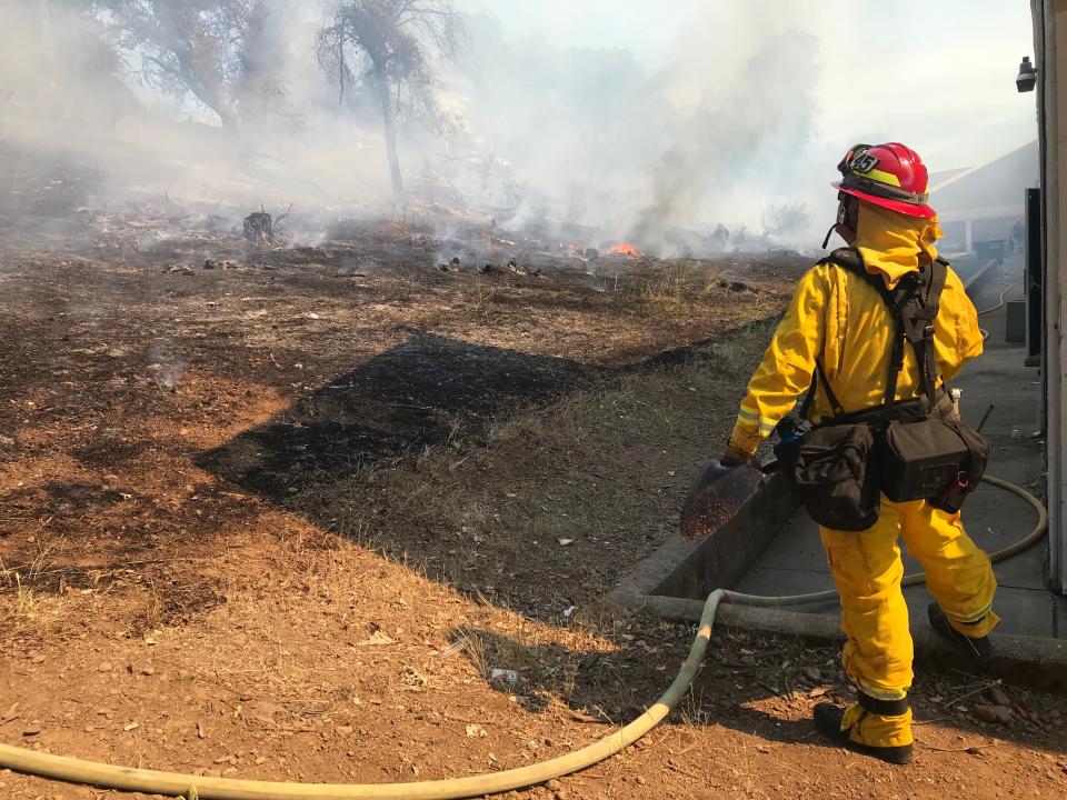 A firefighter stands behind the Showboat Lounge on Hartnell Avenue, where a vegetation fire behind the bar on Hartnell Avenue burned the hillside on Wednesday, May 25, 2022, before forward progress was stopped.