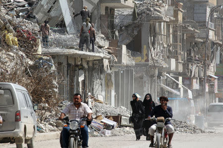 Women walk past rubble of damaged buildings in Raqqa, Syria May 14, 2018. REUTERS/Aboud Hamam/Files