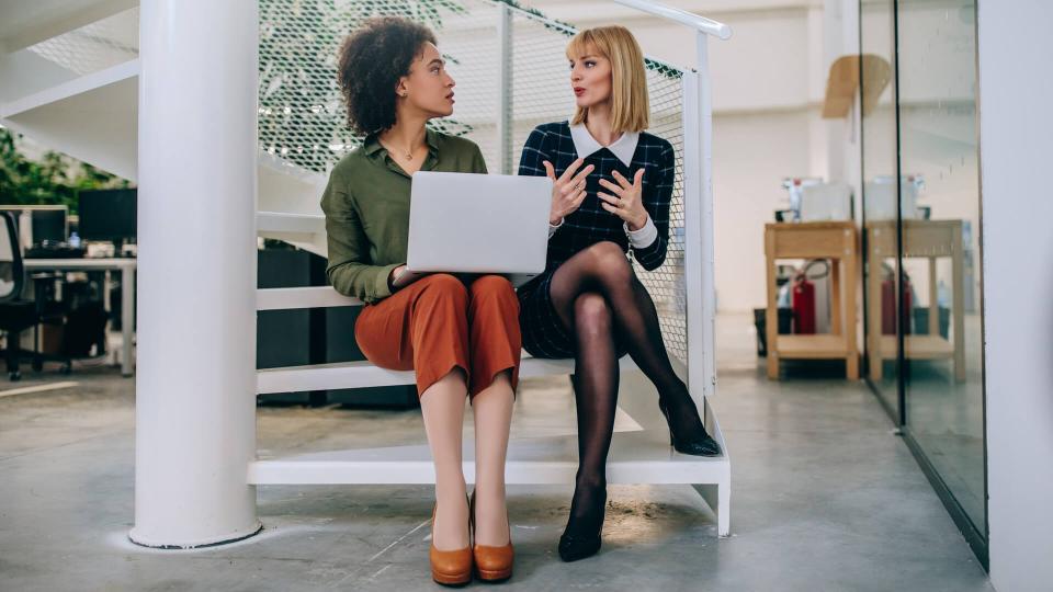 Shot of two businesswomen sitting on the stairs talking.