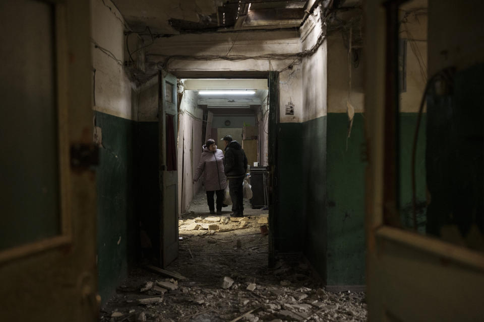 Residents carry belongings from their apartment, heavily damaged after a Russian attack destroyed a building across the street, in Kharkiv, Ukraine, Tuesday, April 12, 2022. (AP Photo/Felipe Dana)