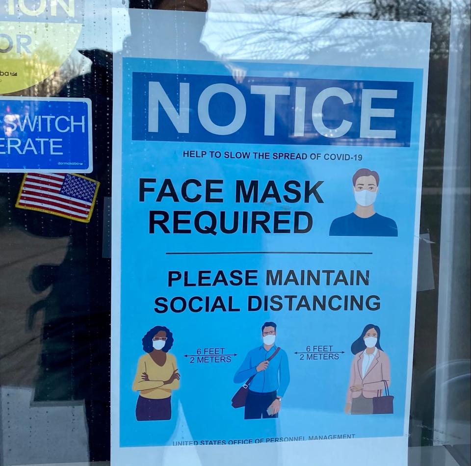 A newly posted sign seen Jan. 21, 2021, on the doors of the federal Office of Personnel Management in Washington, D.C., requires anyone entering to wear a mask, one of the few visible signs of the new administration of President Joe Biden.