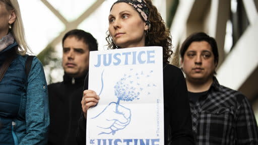 A woman holds a sign that reads "Justice for Justine." (Photo: Yahoo View)