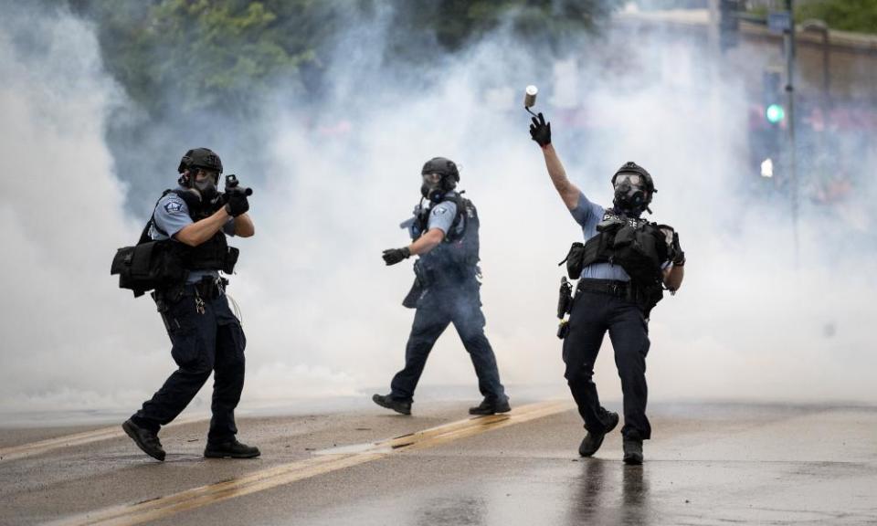 A police officer throws a teargas canister towards protesters.