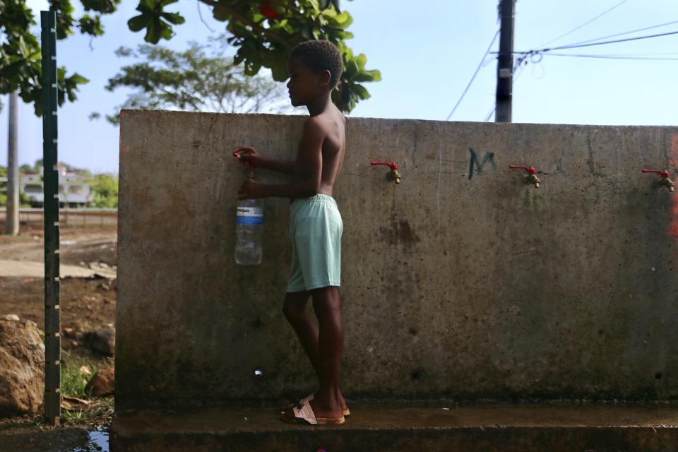 A boy fills up a bottle at the water fountain in M'tsamoudou, near Bandrele on the French Indian Ocean territory of Mayotte, Thursday Oct. 12, 2023. Water taps flow just one day out of three because of a drawn-out drought compounded by years of water mismanagement. (AP Photo/Gregoire Merot)