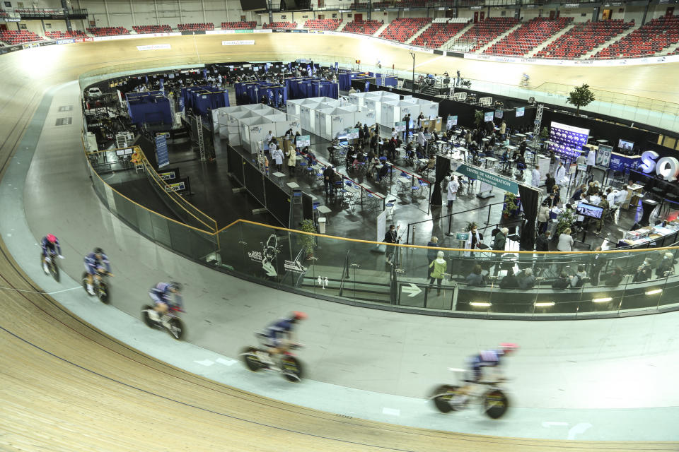 Riders train at the National Velodrome at Saint-Quentin-en-Yvelines, west of Paris, Saturday, March 27, 2021, that has been transformed into a mass vaccination center. Saturday marked the first day in France of vaccination for healthy people aged 70 and above. (AP Photo/John Leicester)