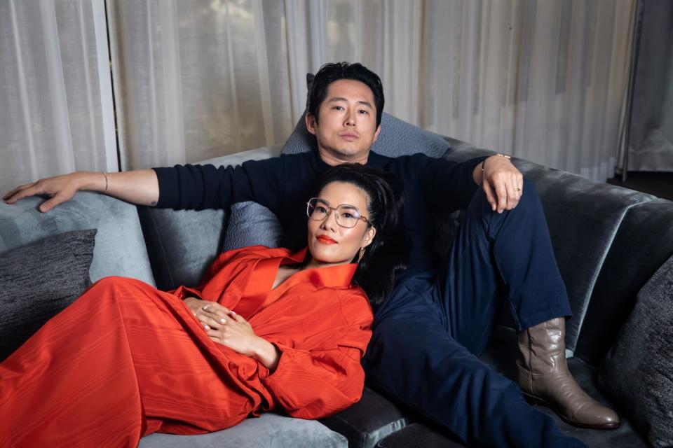 Ali Wong reclines on a couch, resting her head on the seated Steven Yeun's chest.