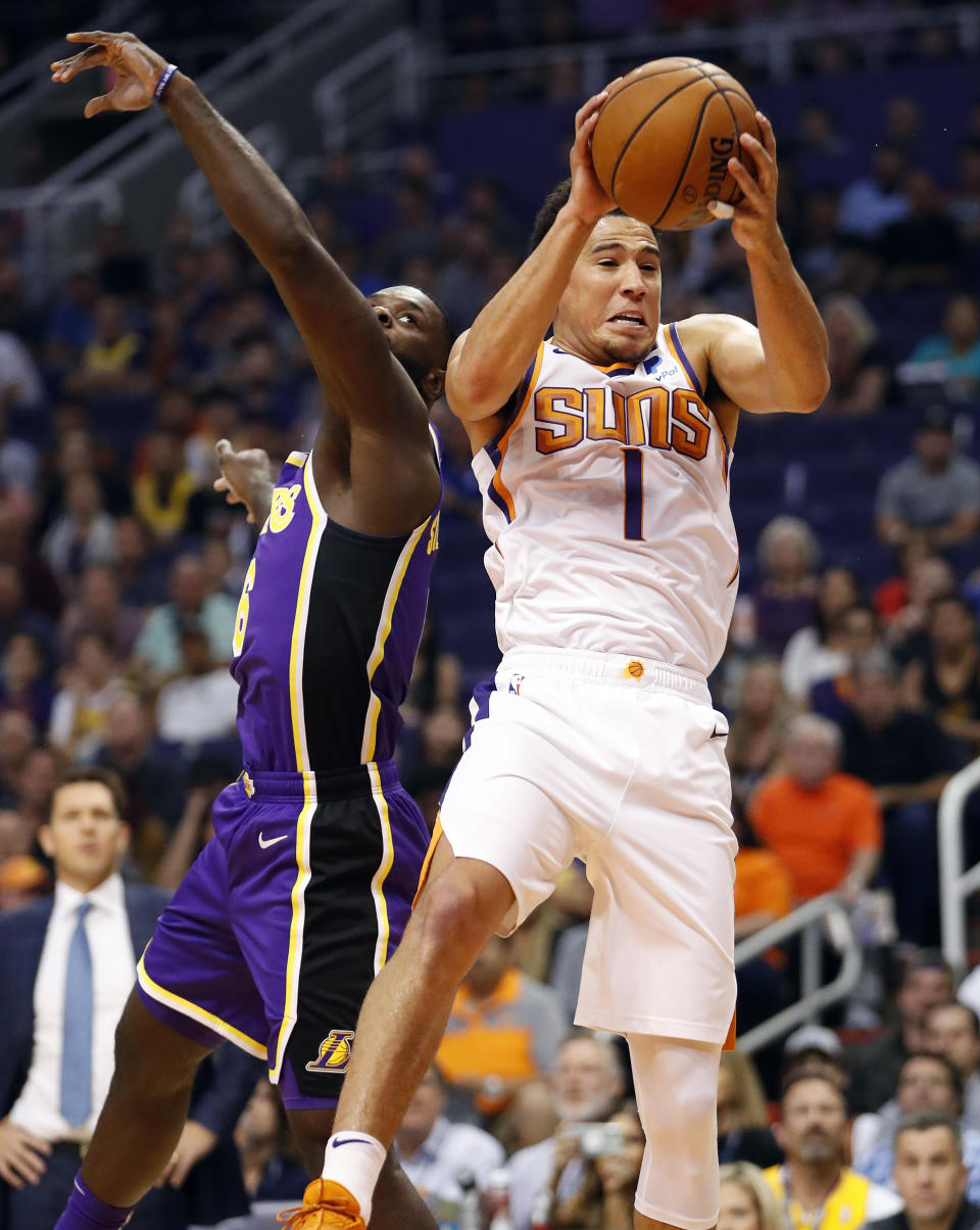 Phoenix Suns guard Devin Booker (1) rebounds over Los Angeles Lakers guard Lance Stephenson during the first half of an NBA basketball game, Wednesday, Oct. 24, 2018, in Phoenix. (AP Photo/Matt York)