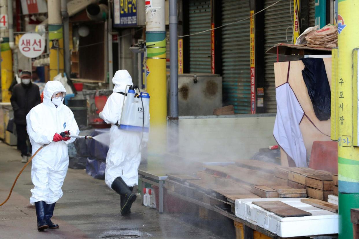 Workers wearing protective gears spray disinfectant as a precaution against the coronavirus at a local market in Busan, South Korea: AP