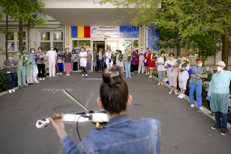 Medical staff of the Polizu maternity hospital listen to a violinist playing to entertain them and the patients in Bucharest, Romania, Tuesday, April 28, 2020. Raluca Raducanu, a young violinist, played a mix of rock and classical pieces during an under one hour performance outside the hospital. (AP Photo/Andreea Alexandru)