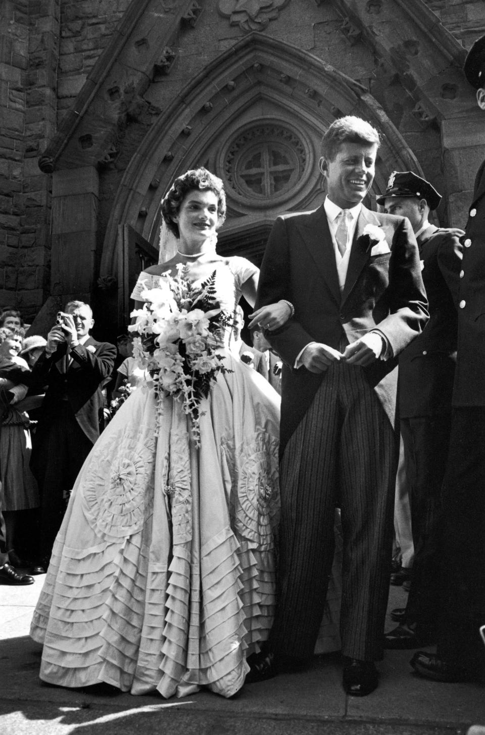 Jacqueline Bouvier in gorgeous Battenburg wedding dress w. her husband Sen. John Kennedy as they stand in front of church after wedding ceremony. (Photo by Lisa Larsen//Time Life Pictures/Getty Images)