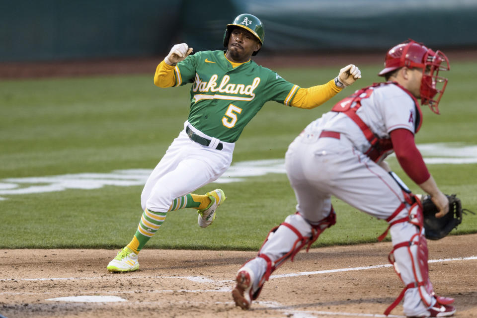 Oakland Athletics' Tony Kemp (5) slides home to score beside Los Angeles Angels catcher Max Stassi, right, during the third inning of a baseball game in Oakland, Calif., Monday, June 14, 2021. (AP Photo/John Hefti)