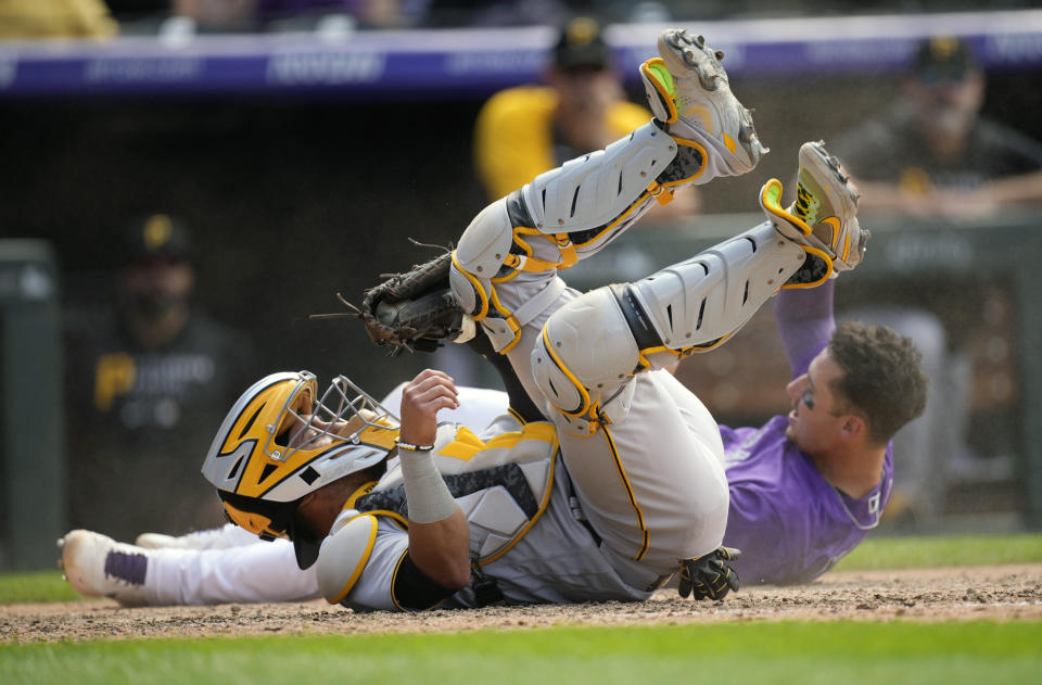 Pittsburgh Pirates catcher Michael Perez, front, tumbles after tagging out Colorado Rockies' Dom Nunez as he tries to score on a single by pinch-hitter Yonathyan Daza in the seventh inning of a baseball game Wednesday, June 30, 2021, in Denver. (AP Photo/David Zalubowski)