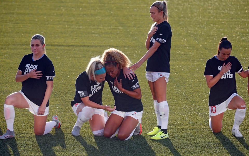 Chicago Red Stars' Julie Ertz, second from left, holds Casey Short, center, while other players for the team kneel during the national anthem before an NWSL Challenge Cup soccer match against the Washington Spirit - AP Photo/Rick Bowmer