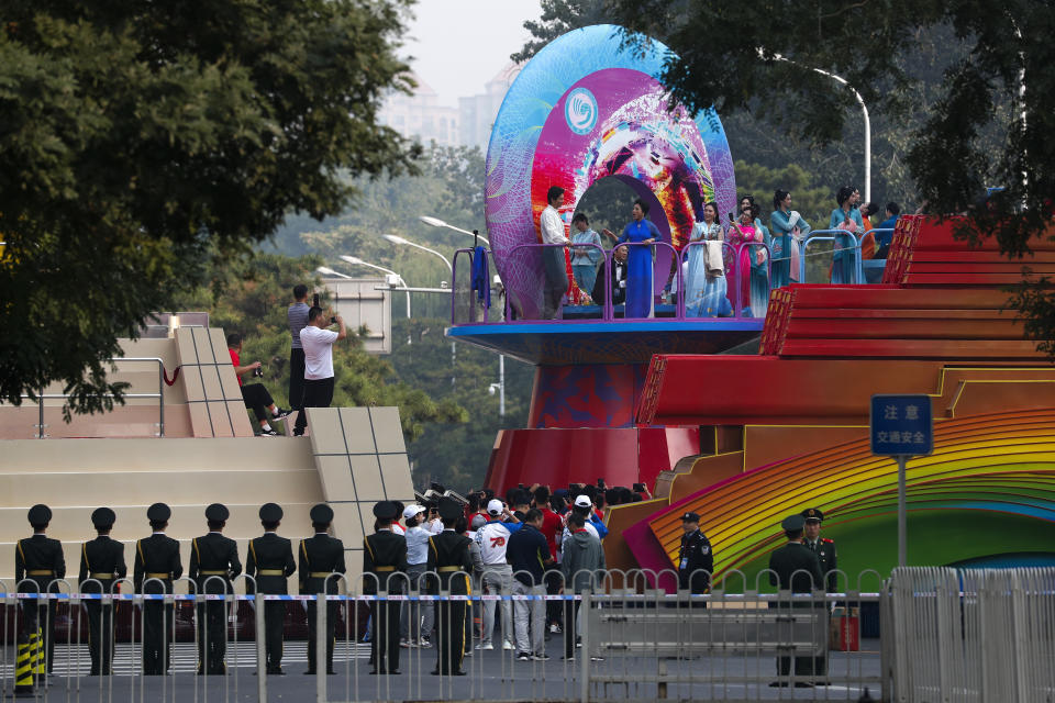 Chinese paramilitary policemen stand guard near the performers practice on a float as Chinese military vehicles and floats in preparation for the parade for the 70th anniversary of the founding of the People's Republic of China, in Beijing, Tuesday, Oct. 1, 2019. (AP Photo/Andy Wong)
