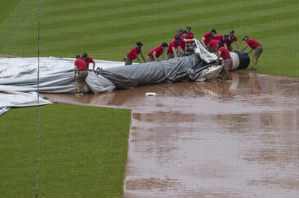 Grounds crew members try to untangle the tarp as they attempt to cover the baseball diamond from a heavy downpour delaying a baseball game during the sixth inning between the Washington Nationals and the Baltimore Orioles in Washington, Sunday, Aug. 9, 2020. (AP Photo/Manuel Balce Ceneta)