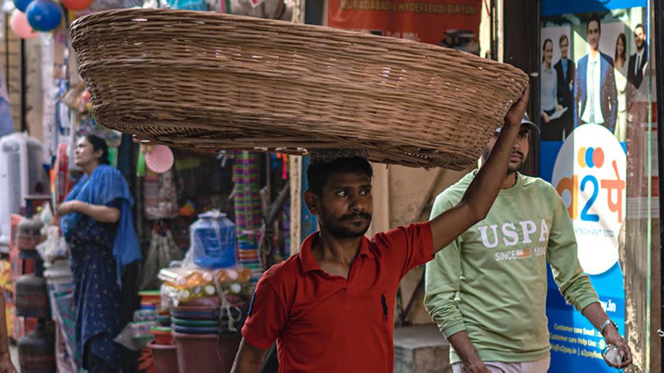 A worker balances a straw basket on his head in Mumbai on April 15, 2024. - Noemi Cassanelli/CNN