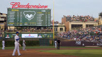 FILE - In this July 28, 2015, file photo, fans at a Wrigley Rooftops' building down the right-field line outside Wrigley Field watch players during the first inning of a baseball game between the Colorado Rockies and Chicago Cubs in Chicago. This week, Major League Baseball players and owners reached an agreement to play an abbreviated, 60-game season that would start July 23 or 24 in teams’ home ballparks. But the seats will be empty. Instead, fans hoping to see a game in person will be have to settle for pressing their faces up against hotel windows, squinting through metal grates or climb to rooftops when baseball returns this month in otherwise empty stadiums. (AP Photo/Andrew A. Nelles, File)