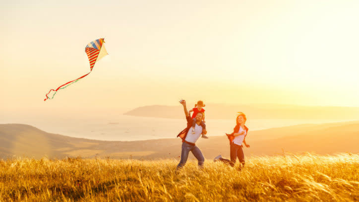 Happy family father of mother and child daughter launch a kite on nature at sunset