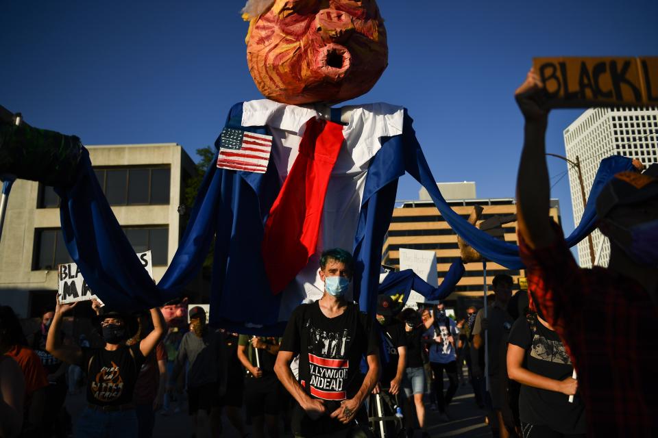 Protestors for "Black Lives Matter" hold a caricature of the president as they demonstrate in Tulsa, Oklahoma where Donald Trump holds a campaign rally at the BOK Center on June 20, 2020. - Hundreds of supporters lined up early for Donald Trump's first political rally in months, saying the risk of contracting COVID-19 in a big, packed arena would not keep them from hearing the president's campaign message. (Photo by Brendan Smialowski / AFP) (Photo by BRENDAN SMIALOWSKI/AFP via Getty Images)