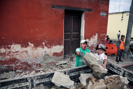 A municipal worker and a firefighter (R) remove debris from a damaged house after an earthquake in Antigua, Guatemala June 22, 2017. REUTERS/Luis Echeverria NO RESALES. NO ARCHIVES