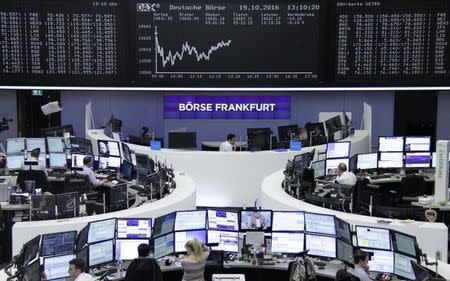 Traders work at their desks in front of the German share price index, DAX board, at the stock exchange in Frankfurt, Germany, October 19, 2016. REUTERS/Staff/Remote -