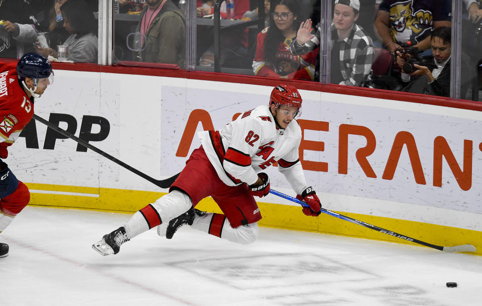 Carolina Hurricanes center Jesperi Kotkaniemi (82) dives for the puck in front of Florida Panthers center Sam Reinhart (13) during the first period of an NHL hockey game Friday, Nov. 10, 2023, in Sunrise, Fla. (AP Photo/Michael Laughlin)