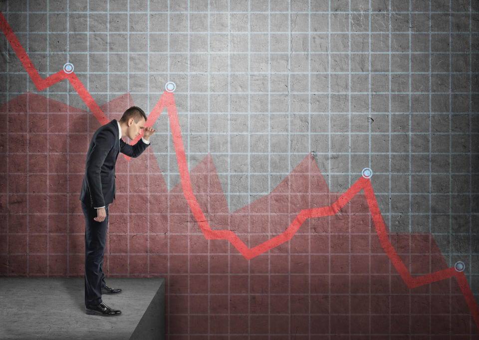 Side view of a businessman shading his eyes with his hand looking at falling diagram. Economic and financial crisis. Stock market selloff.