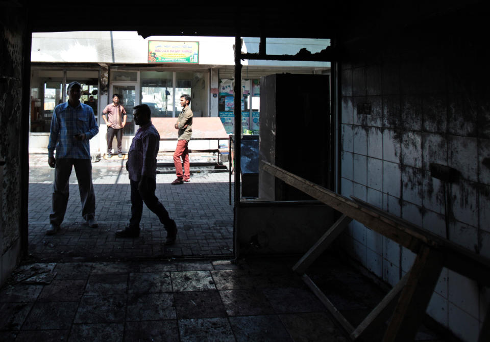 Asian workers inspect their shop after several shops and a market near the police station were damaged by people hurling petrol bombs in Sitra, Bahrain, Tuesday, May 6, 2014. Bahraini police have confronted attackers who tried to firebomb a police post in a largely Shiite community in the tiny Gulf island nation, authorities said Tuesday. (AP Photo/Hasan Jamali)