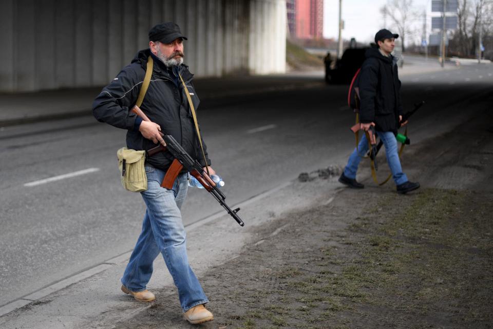 Volunteers, one holding an AK-47 rifle, protect a main road leading into Kyiv on February 25, 2022. / Credit: DANIEL LEAL/AFP/Getty