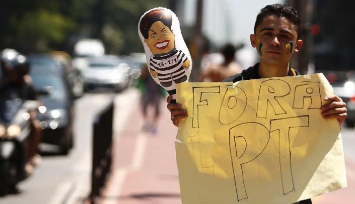 A demonstrator holds a balloon depicting Brazilian President Dilma Rousseff as he holds a sign reading "PT out", in Sao Paulo, Brazil on March 19, 2016 (AFP Photo/Miguel Schincariol)