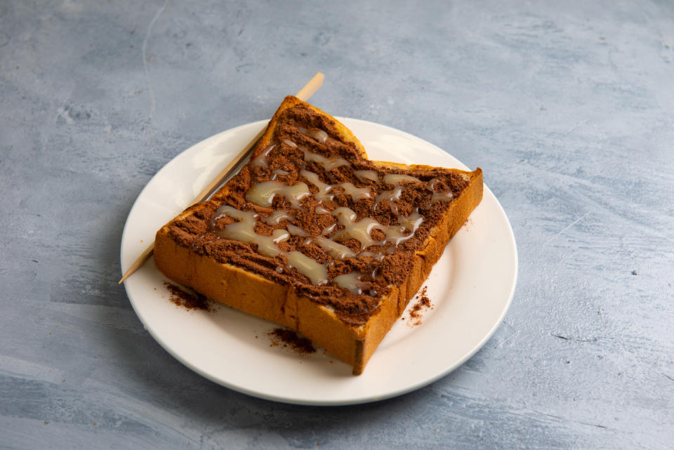 A plate of thick toast with chocolate malt power on it, topped with condensed milk.