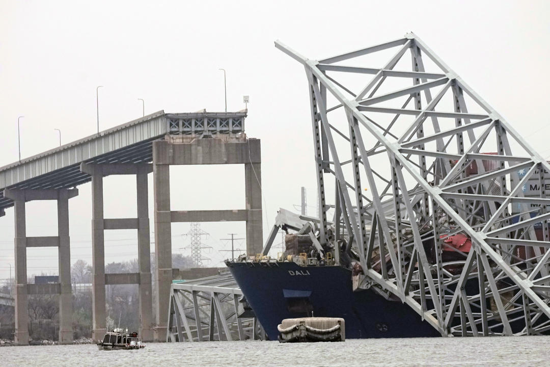 A cargo ship stuck under part of a bridge structure.