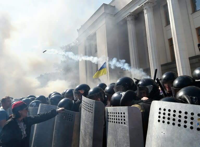 A demonstrator holds a police officer's shield in front of the parliament building in Kiev during clashes with police officers on August 31, 2015