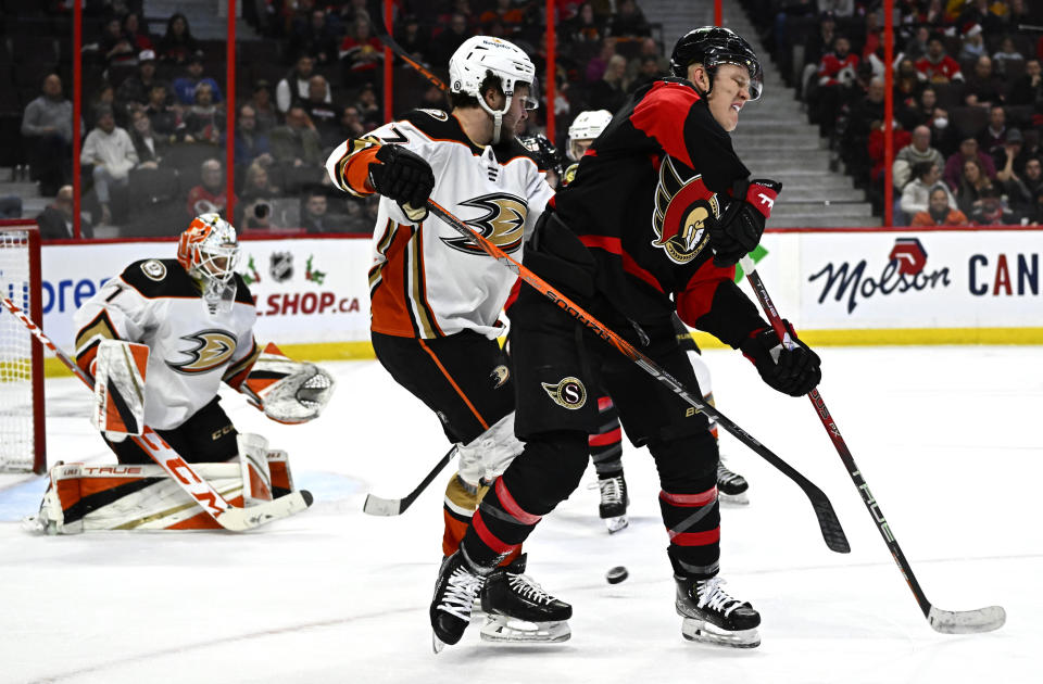 Ottawa Senators left wing Brady Tkachuk (7) redirects the puck back toward Anaheim Ducks goaltender Lukas Dostal (1) as Ducks center Mason McTavish (37) defends during second-period NHL hockey game action in Ottawa, Ontario, Monday, Dec. 12, 2022. (Justin Tang/The Canadian Press via AP)