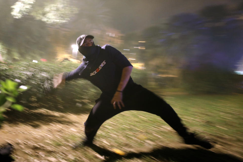 A protestor hurls a rock at police during clashes in Barcelona, Spain, Wednesday, Oct. 16, 2019. Spain's government said Wednesday it would do whatever it takes to stamp out violence in Catalonia, where clashes between regional independence supporters and police have injured more than 200 people in two days. (AP Photo/Emilio Morenatti)