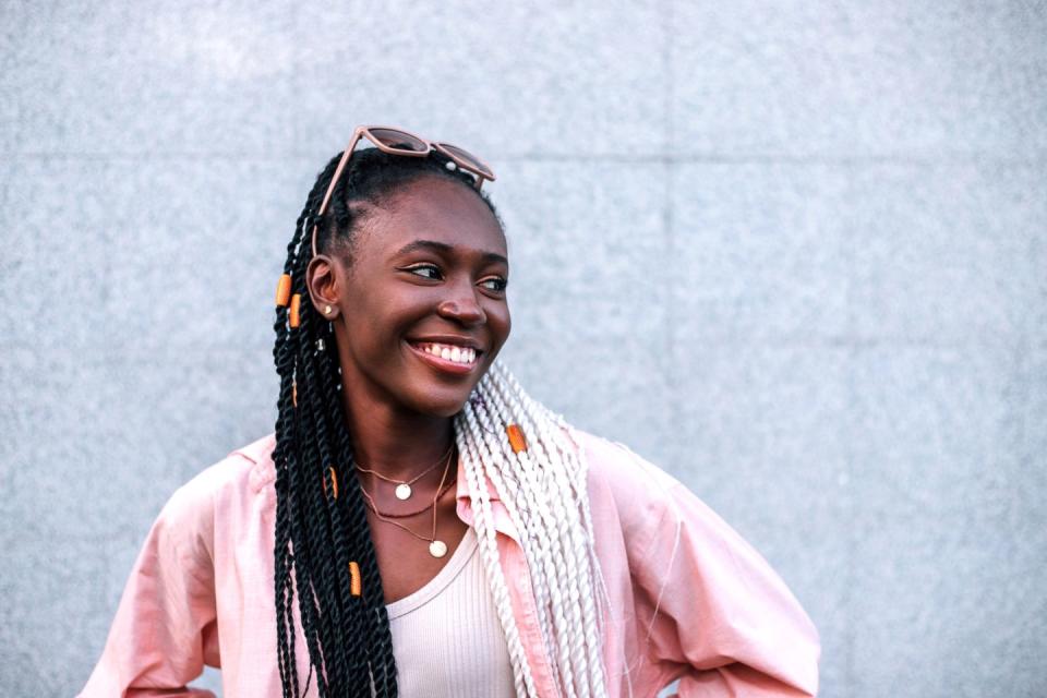 young black braided woman smiling outdoors